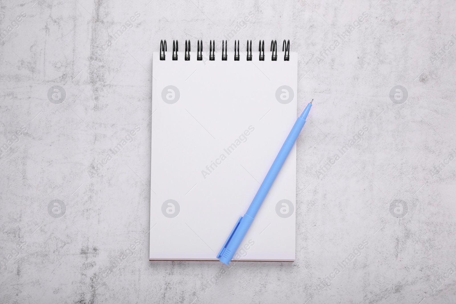 Photo of Notebook and blue marker on light grey background, top view