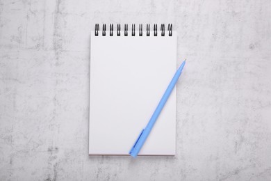 Photo of Notebook and blue marker on light grey background, top view
