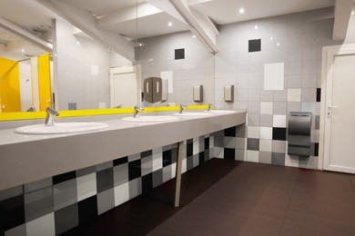 Public toilet interior with sinks, mirror and colorful tiles