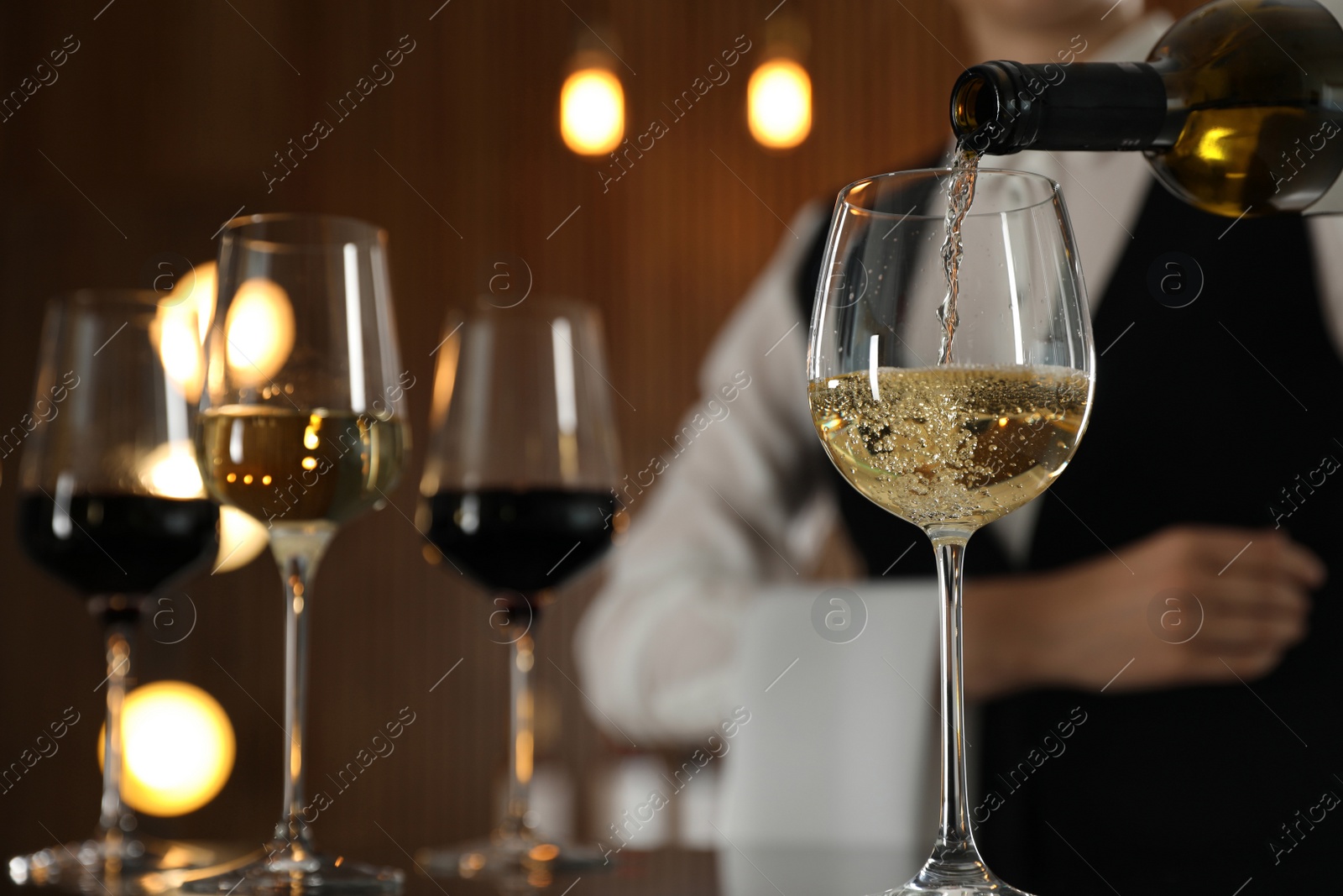 Photo of Waitress pouring wine into glass in restaurant, closeup