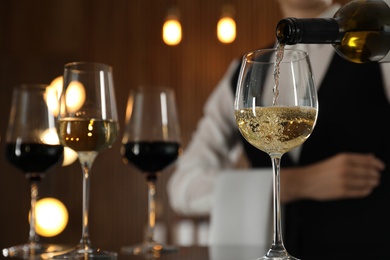 Waitress pouring wine into glass in restaurant, closeup