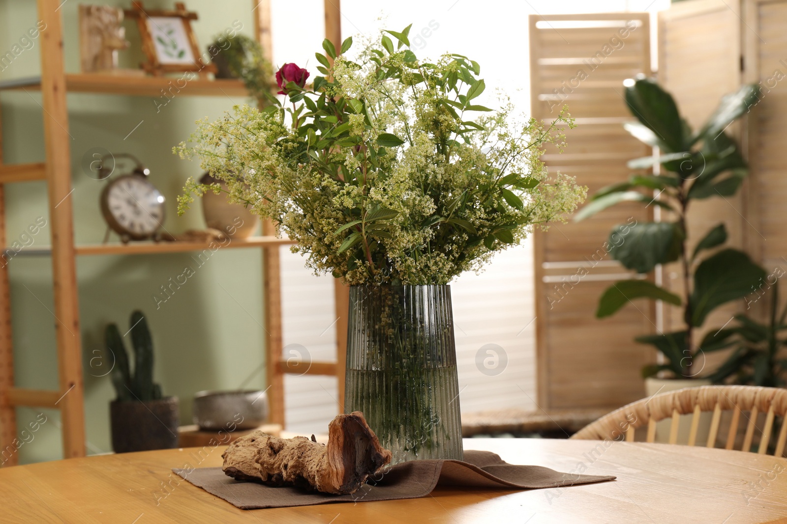 Photo of Vase with beautiful flowers on wooden table in stylish dining room