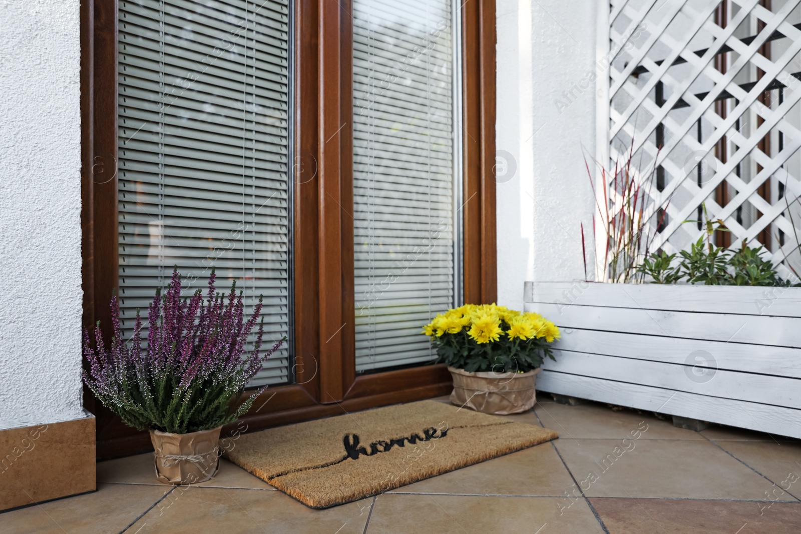 Photo of Doormat with word Home and flowers near entrance outdoors