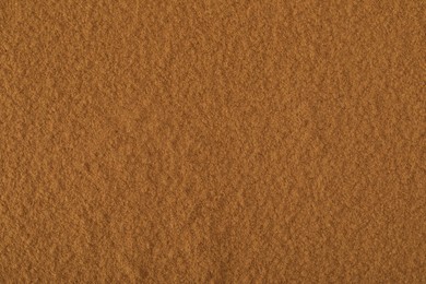 Photo of Dry aromatic cinnamon powder as background, top view