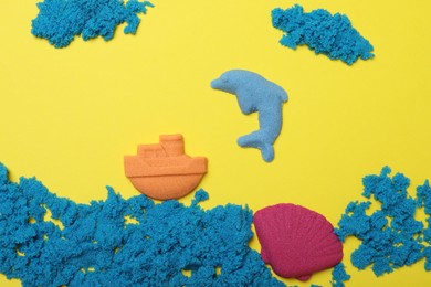 Photo of Sea inhabitants made of kinetic sand on yellow background, flat lay
