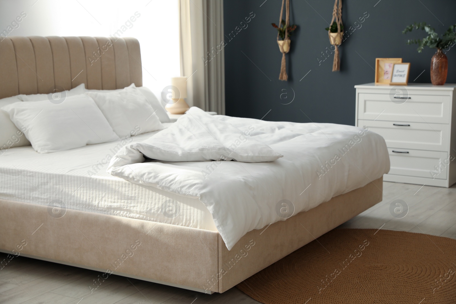Photo of Comfortable bed with soft blanket in stylish room interior