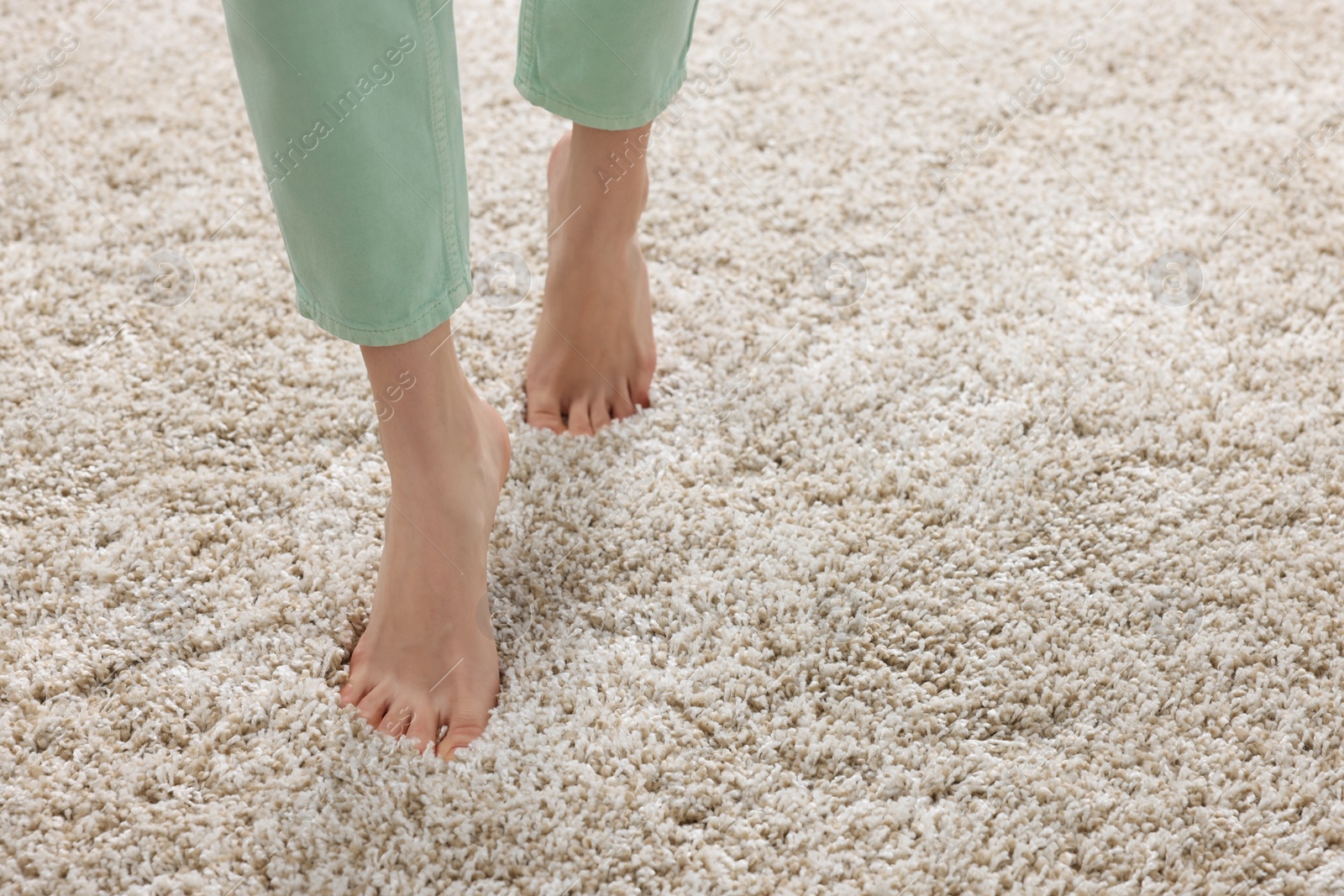 Photo of Woman walking on soft light brown carpet at home, closeup. Space for text