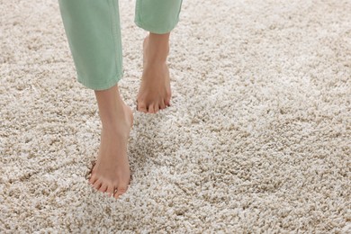 Woman walking on soft light brown carpet at home, closeup. Space for text