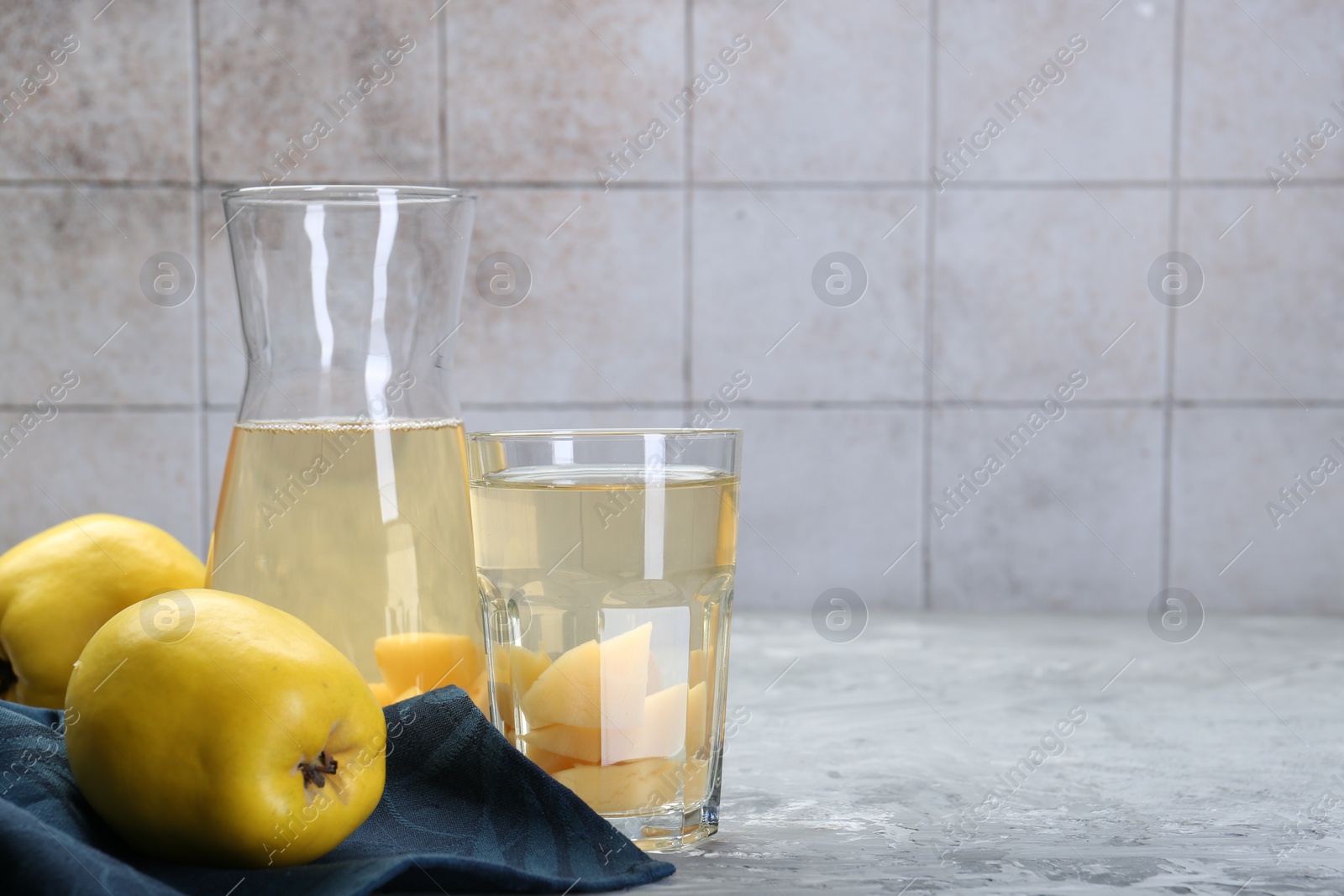 Photo of Delicious quince drink and fresh fruits on grey table. Space for text