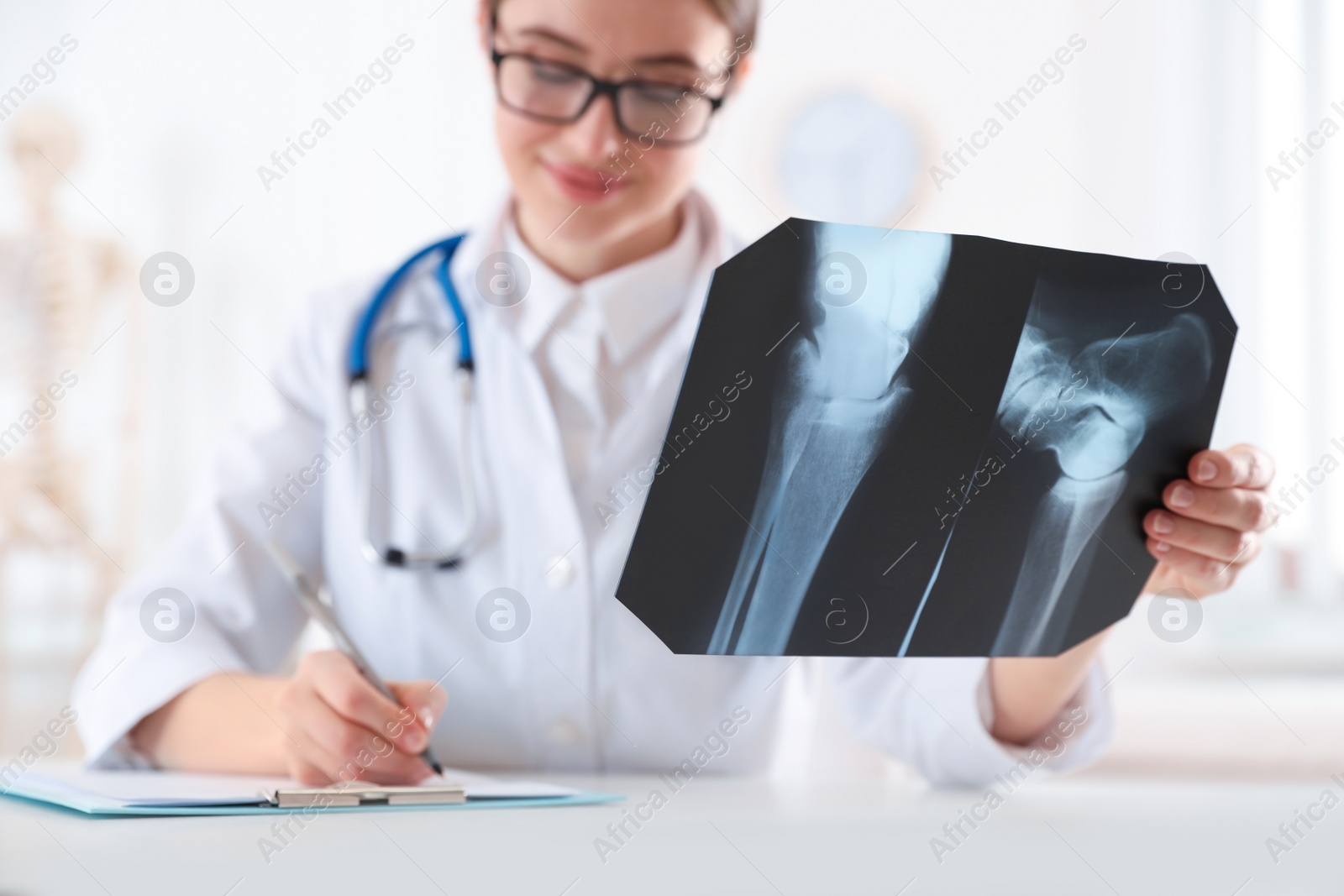 Photo of Orthopedist examining radiography at desk in office, focus on X-ray picture