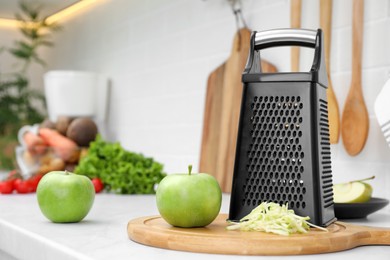 Photo of Grater and fresh ripe apples on kitchen counter