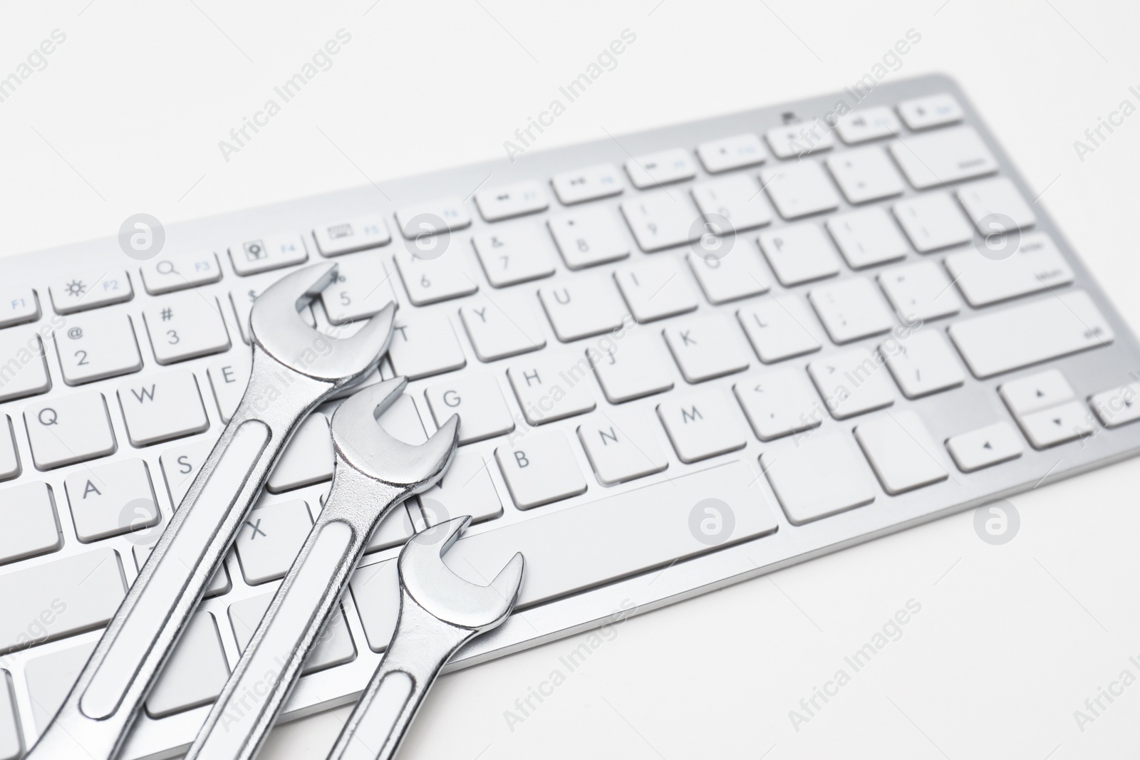 Photo of Wrenches and computer keyboard on light background. Concept of technical support