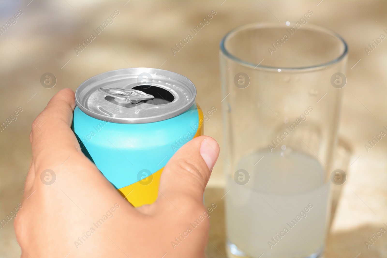 Photo of Woman holding aluminum can with drink on blurred background, closeup