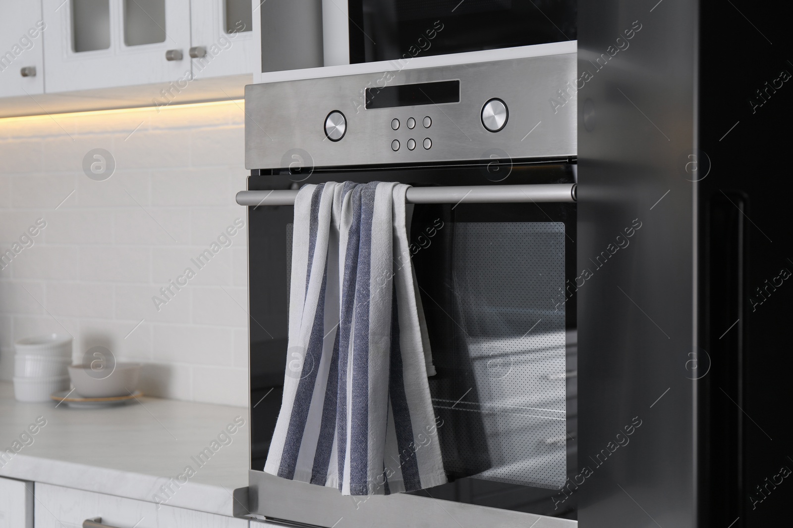 Photo of Clean striped towel on oven door in kitchen