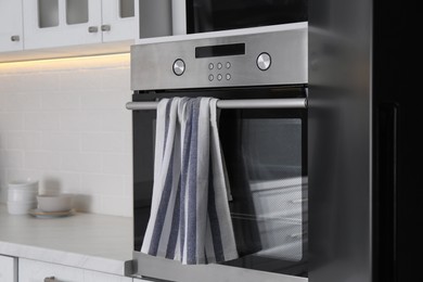 Photo of Clean striped towel on oven door in kitchen