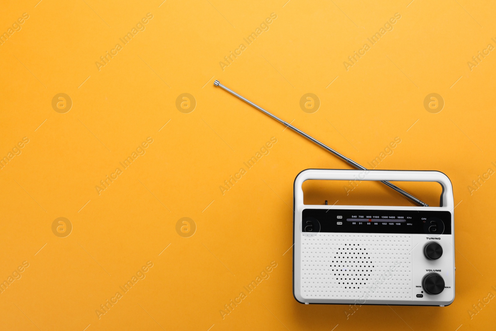 Photo of Retro radio receiver on orange background, top view. Space for text