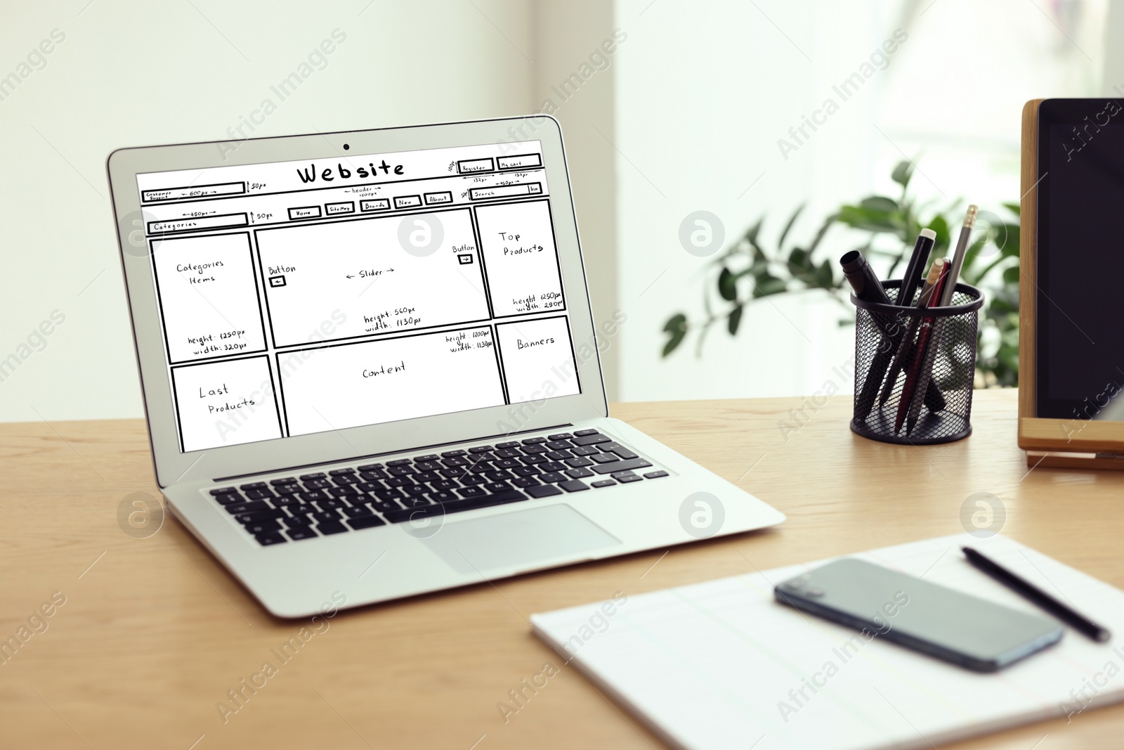 Image of Laptop with sketch of website planning and design on wooden table