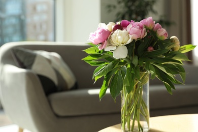 Photo of Vase with bouquet of beautiful peonies on table in room, space for text