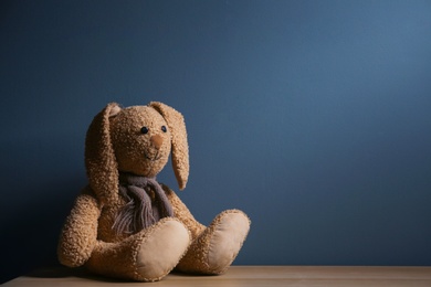 Photo of Abandoned toy bunny on table against dark background. Time to visit child psychologist