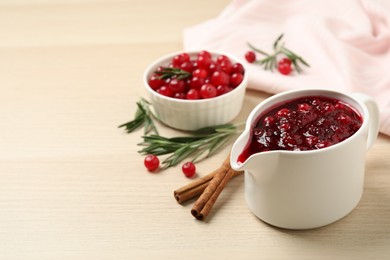 Photo of Cranberry sauce in pitcher on wooden table, space for text
