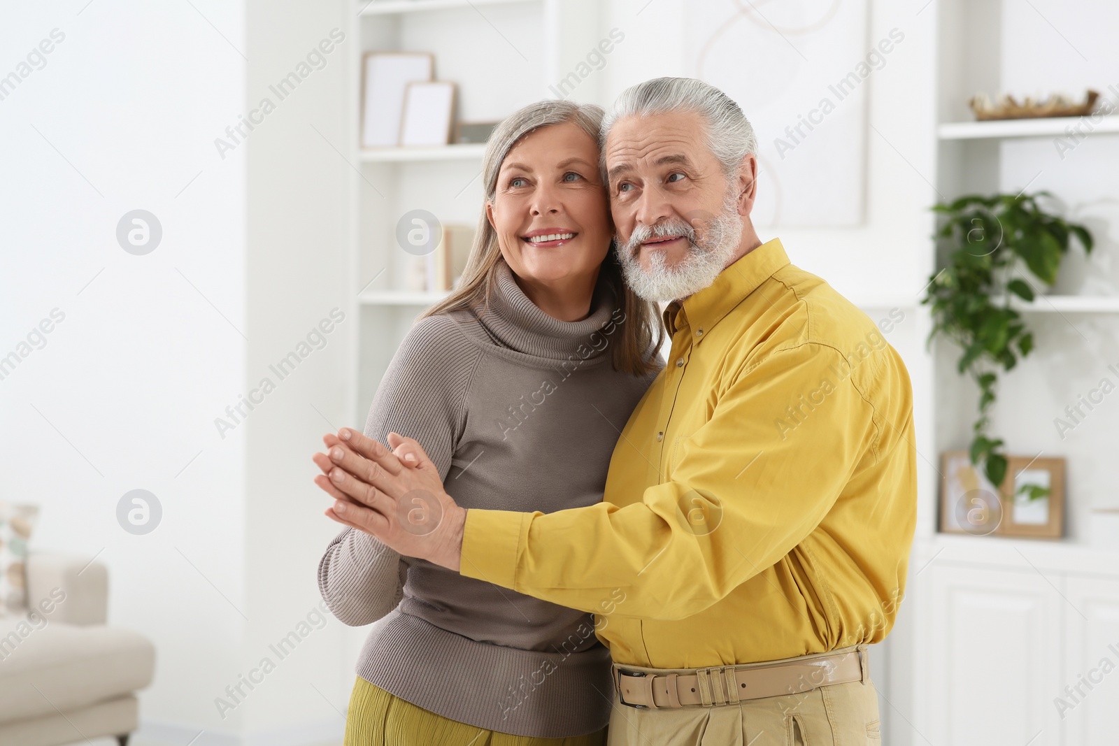 Photo of Affectionate senior couple dancing in living room at home