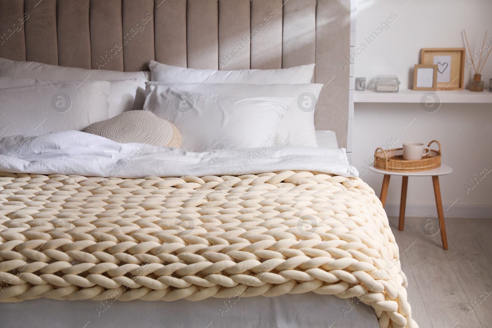 Photo of Soft chunky knit blanket on bed in stylish room interior