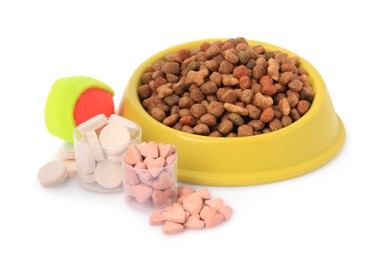 Photo of Dry pet food in bowl, vitamins and toy isolated on white
