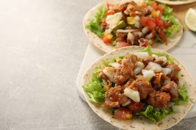 Photo of Delicious tacos with vegetables and meat on light table, space for text