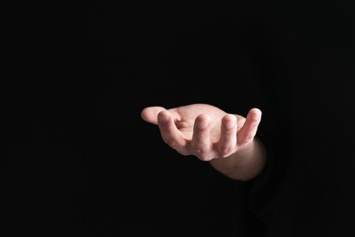 Photo of Man holding something in his hand on black background, closeup
