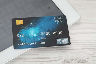 Online payment concept. Bank card and tablet on white wooden table, closeup