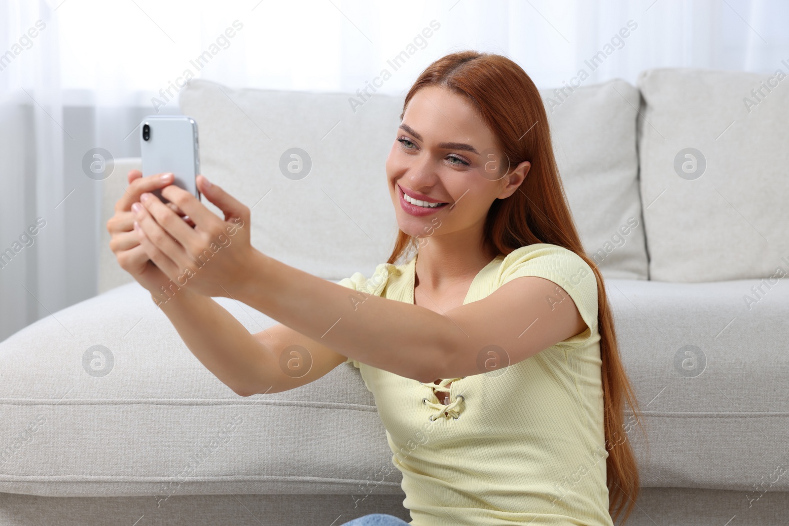 Photo of Happy young woman having video chat via smartphone at home