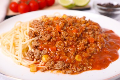 Tasty dish with fried minced meat, spaghetti, carrot and corn in plate, closeup