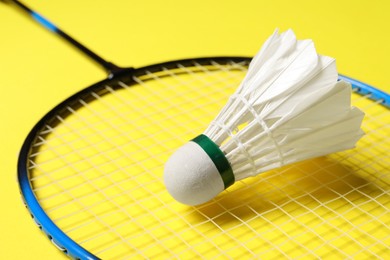 Photo of Feather badminton shuttlecock and racket on yellow background, closeup