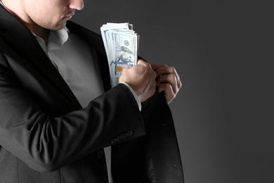 Photo of Man putting bribe money into pocket on black background, closeup. Space for text