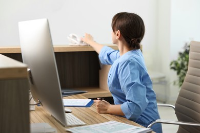 Medical assistant reaching for phone in office