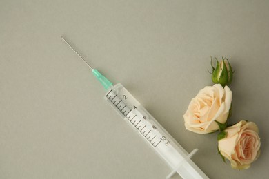 Photo of Medical syringe and rose flowers on light grey background, flat lay