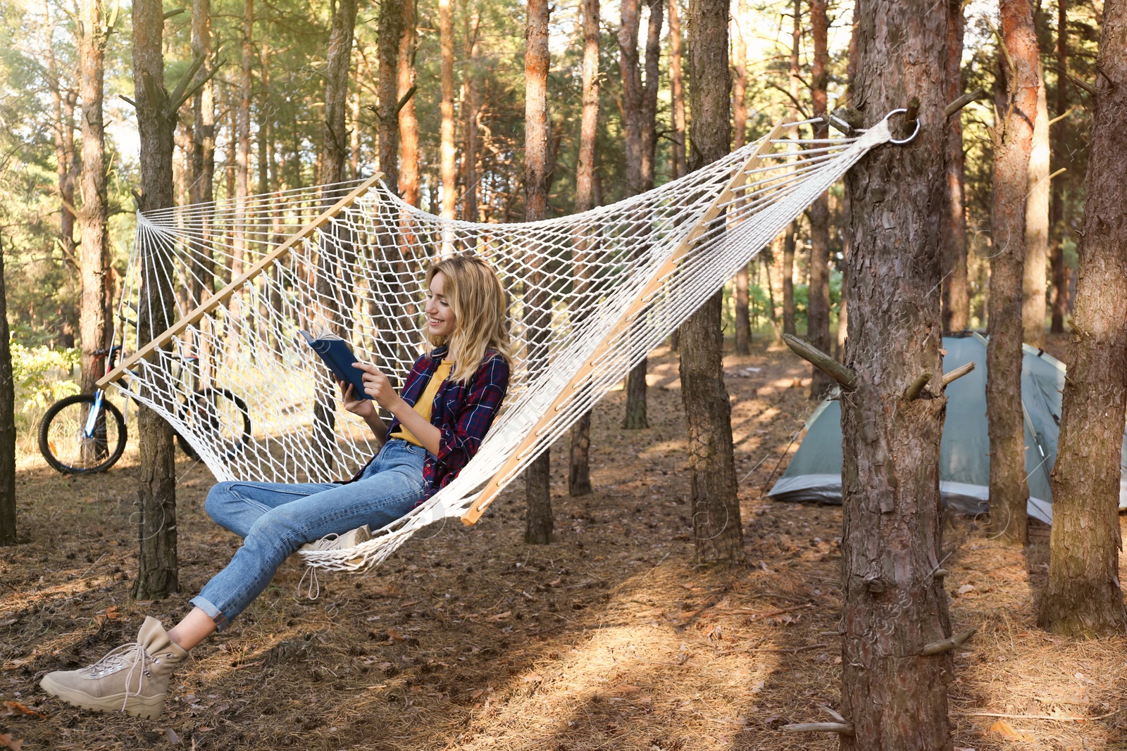 Photo of Beautiful young woman with book relaxing in hammock outdoors on summer day