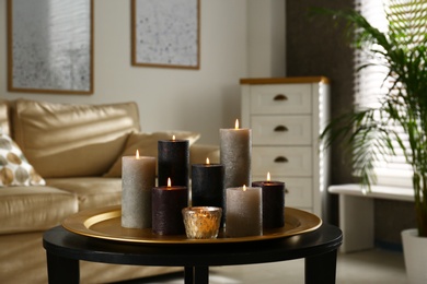 Photo of Tray with different burning candles on table in room