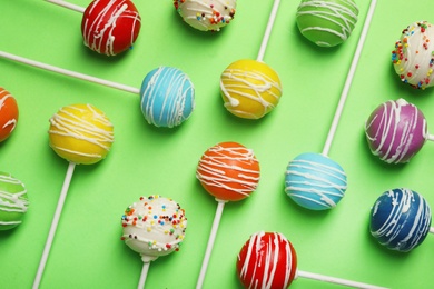 Bright delicious cake pops on color background, flat lay