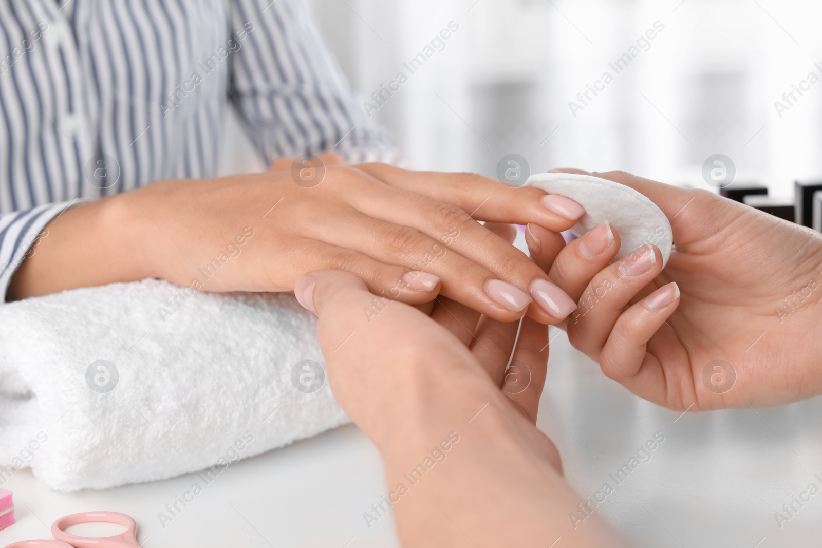 Photo of Manicurist removing polish from client's nails in salon, closeup