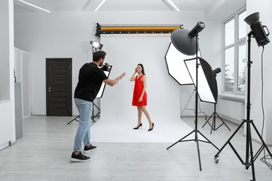 Professional photographer working with beautiful model in modern photo studio