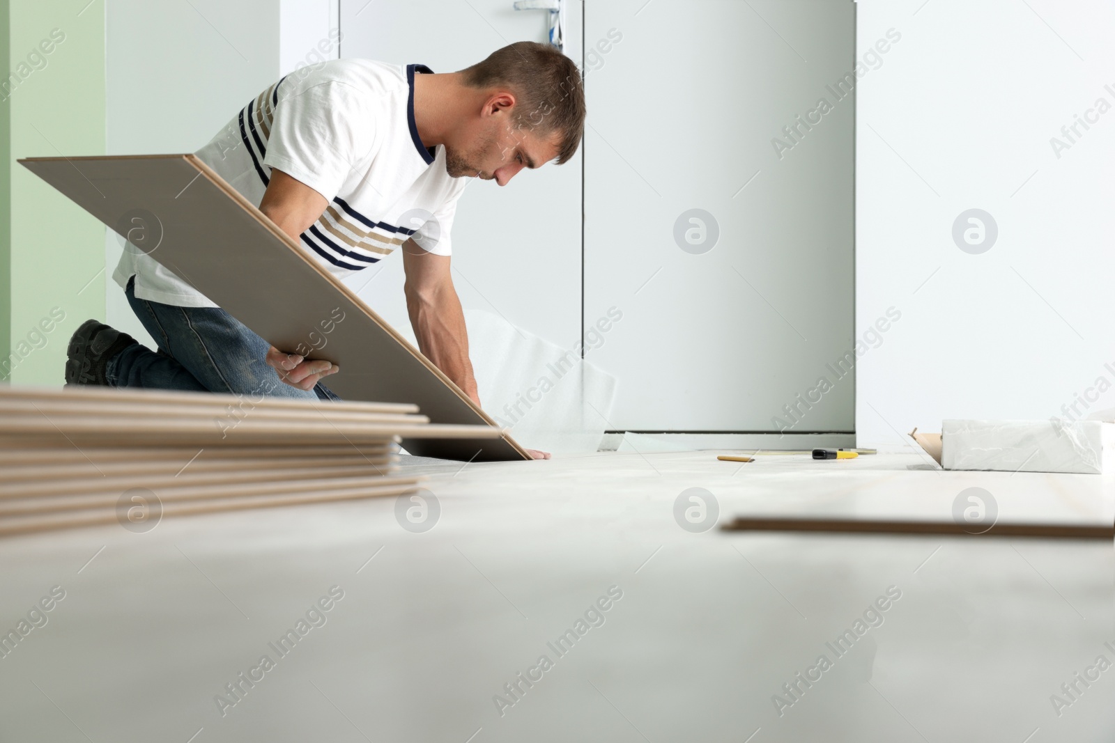 Photo of Man installing new laminate flooring in room