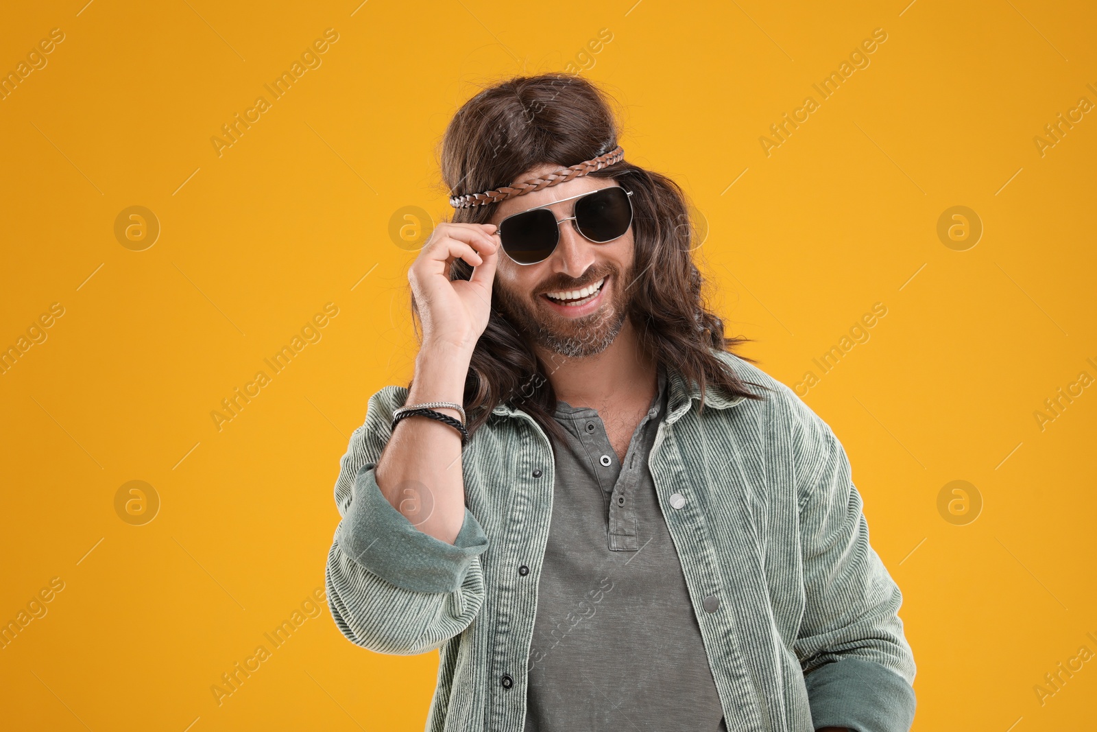 Photo of Stylish hippie man in sunglasses on orange background