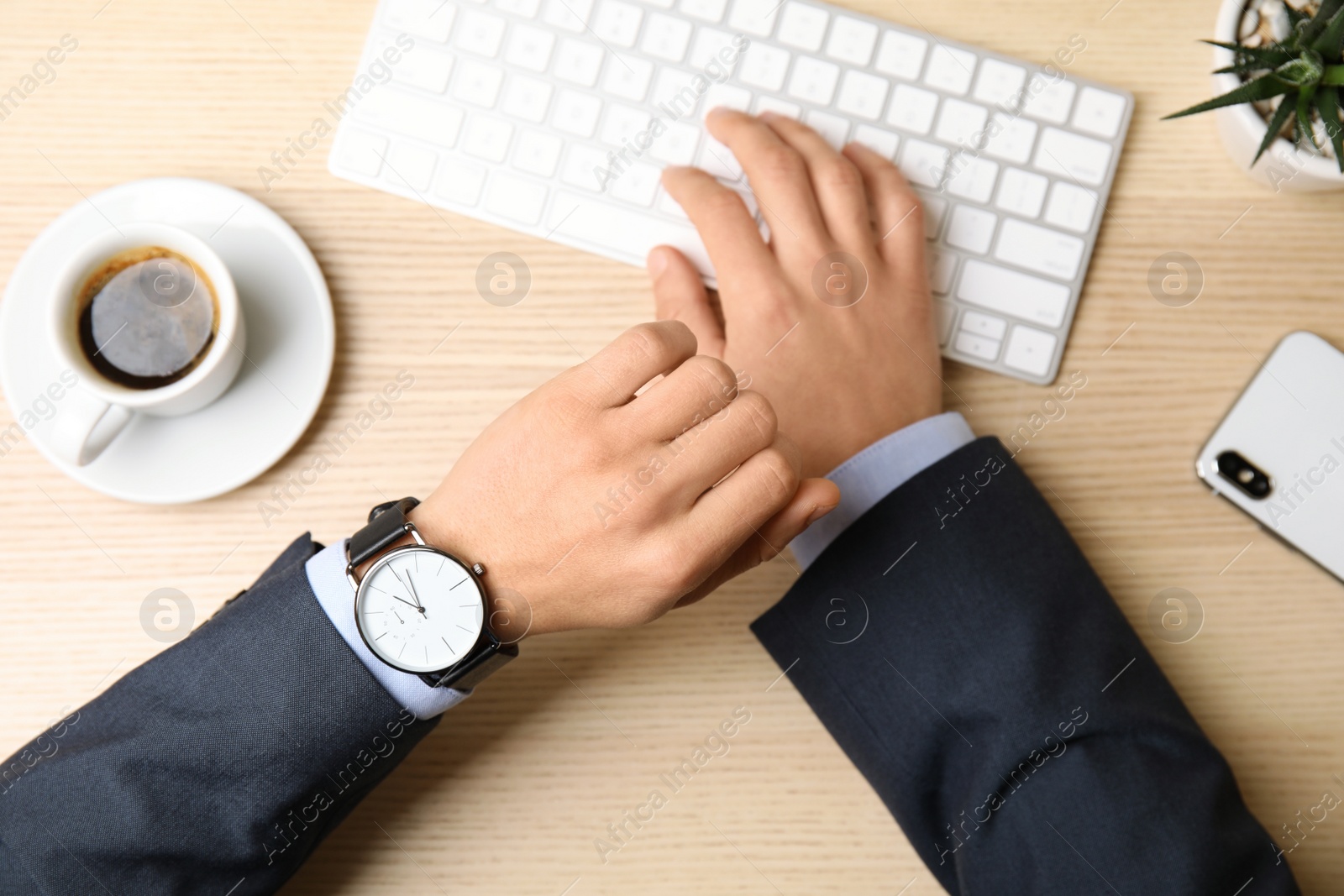 Photo of Businessman with wrist watch working at office table, closeup. Time management