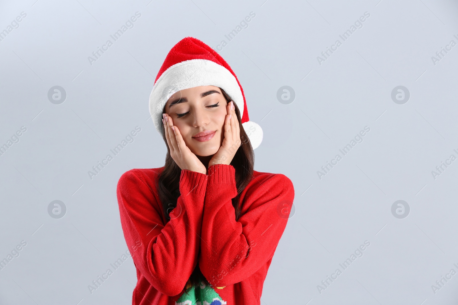 Photo of Beautiful woman wearing Santa Claus hat on light grey background