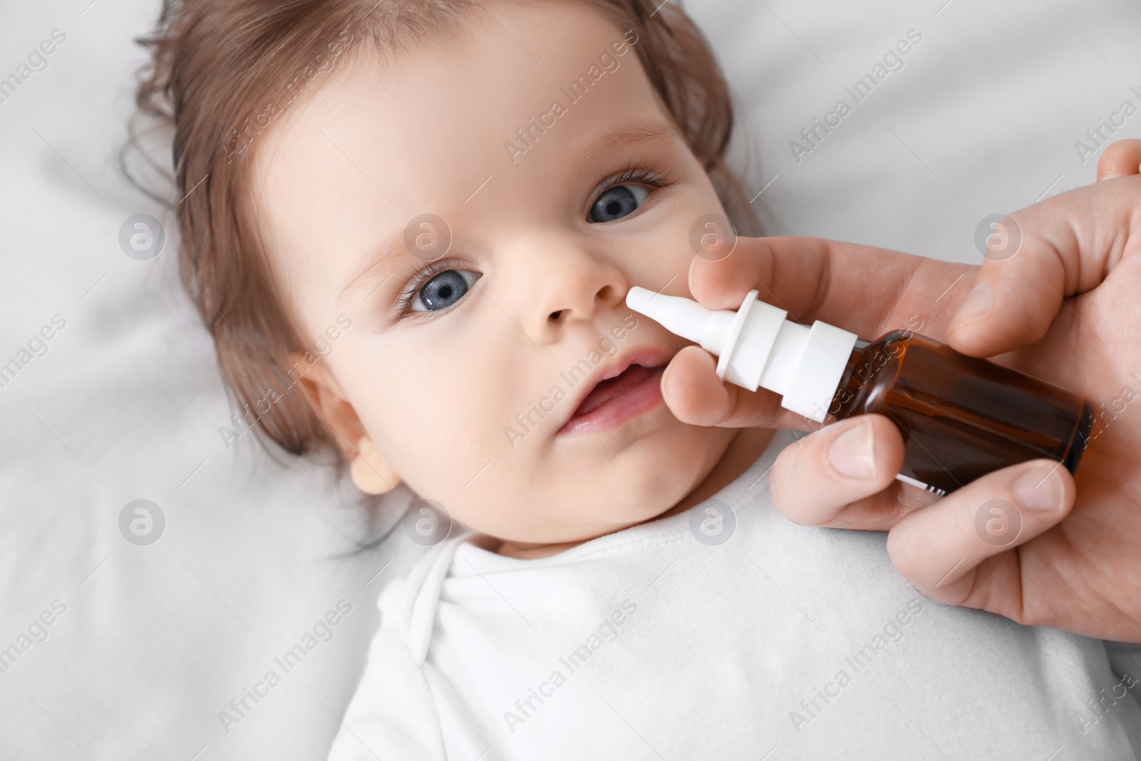 Photo of Father taking care of little baby suffering from runny nose in bed, top view