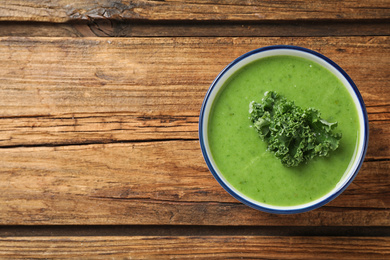 Photo of Tasty kale soup on wooden table, top view. Space for text