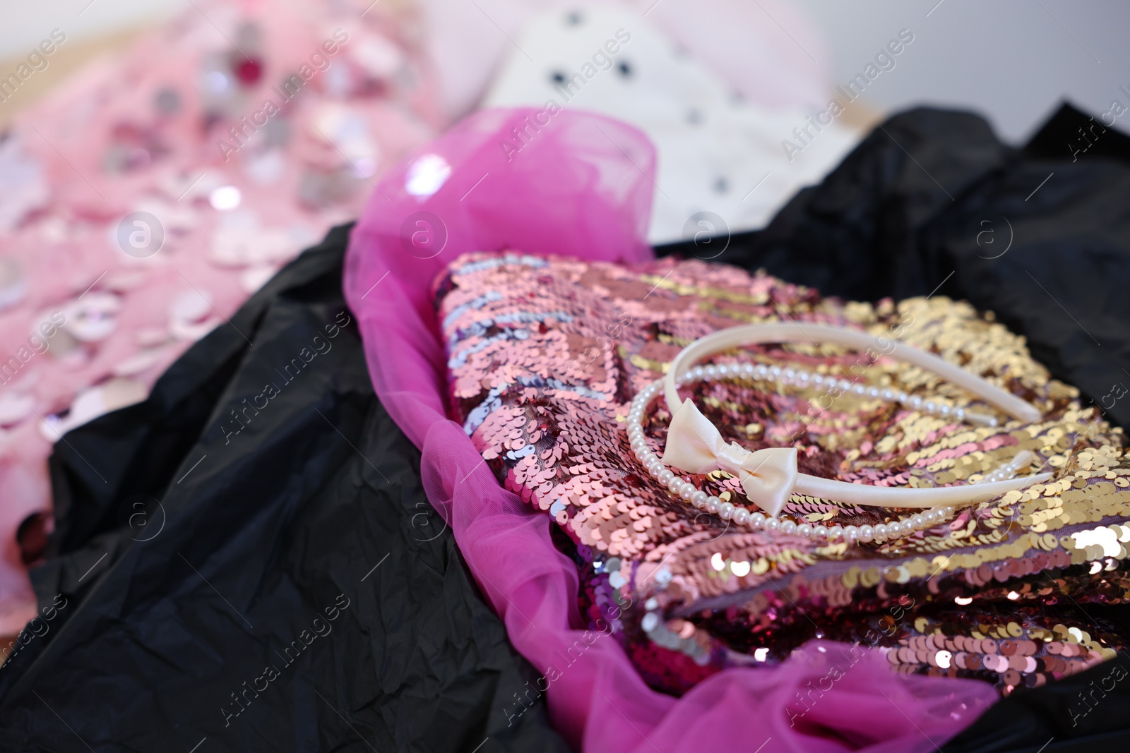 Photo of Headbands and stylish pink carnival costume with sequins in black box, closeup