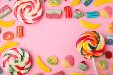 Photo of Frame of many different jelly candies and lollipops on pink background, flat lay. Space for text