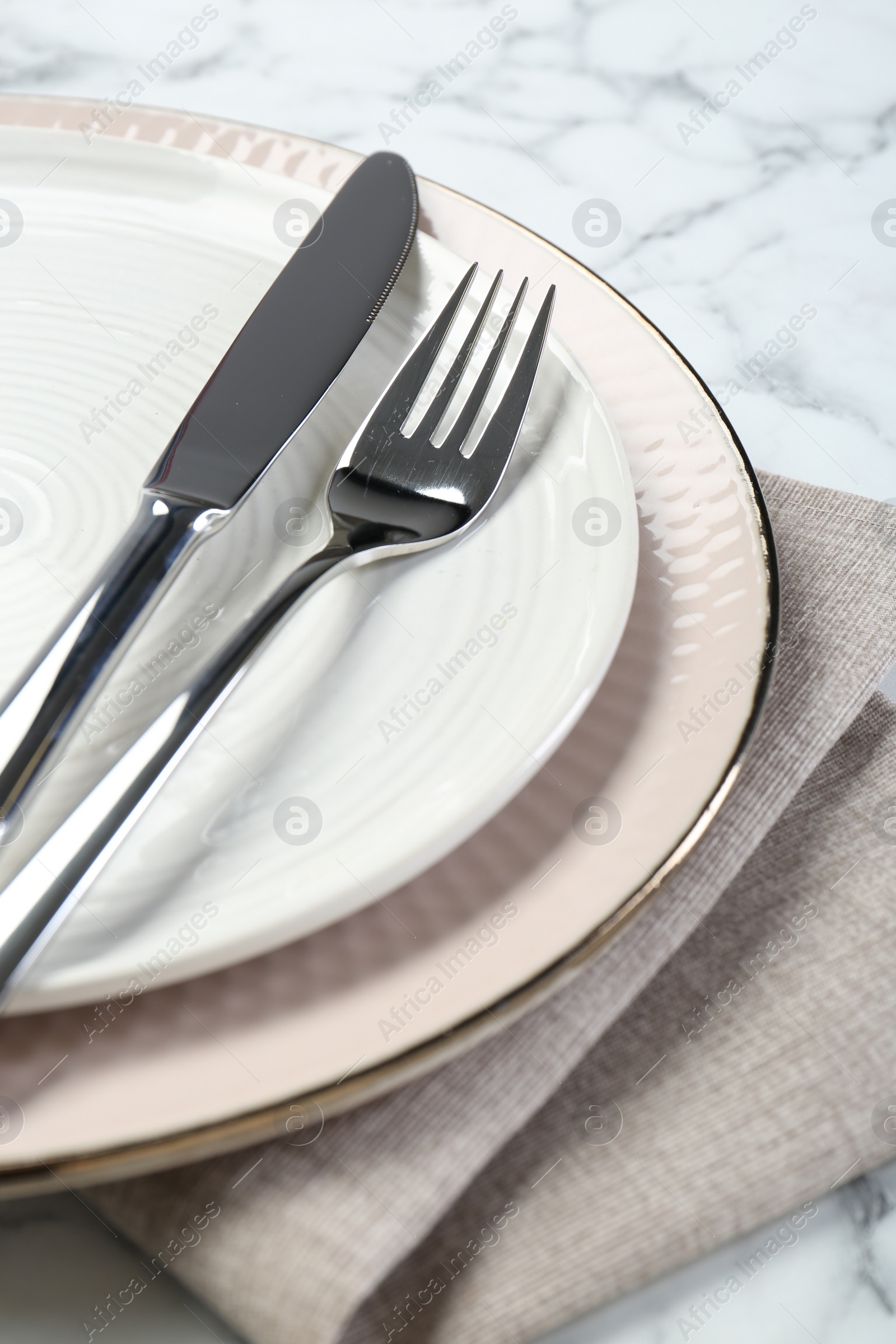 Photo of Clean plates, cutlery and napkin on table, closeup